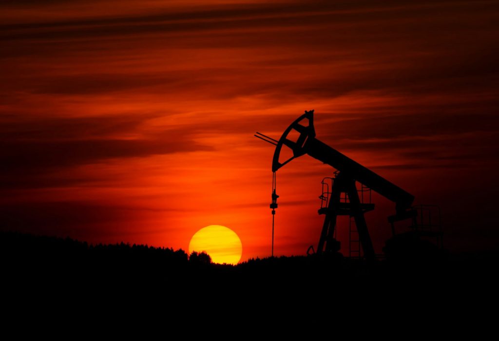 Oil pump silhouetted against vibrant orange sunset.