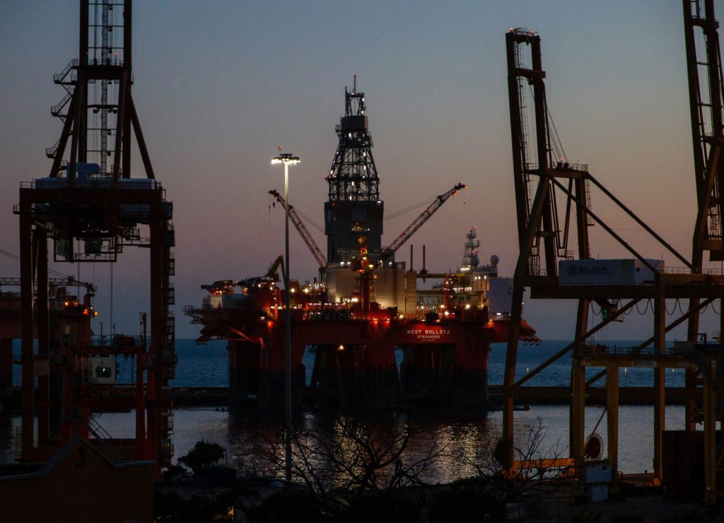 Oil platform illuminated at night near shore